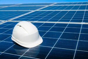 A white hard hat resting on blue solar panels